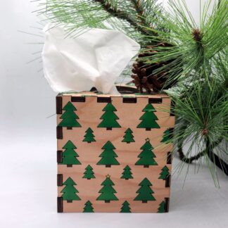 a hand painted pine trees tissue box cover next to a pine tree